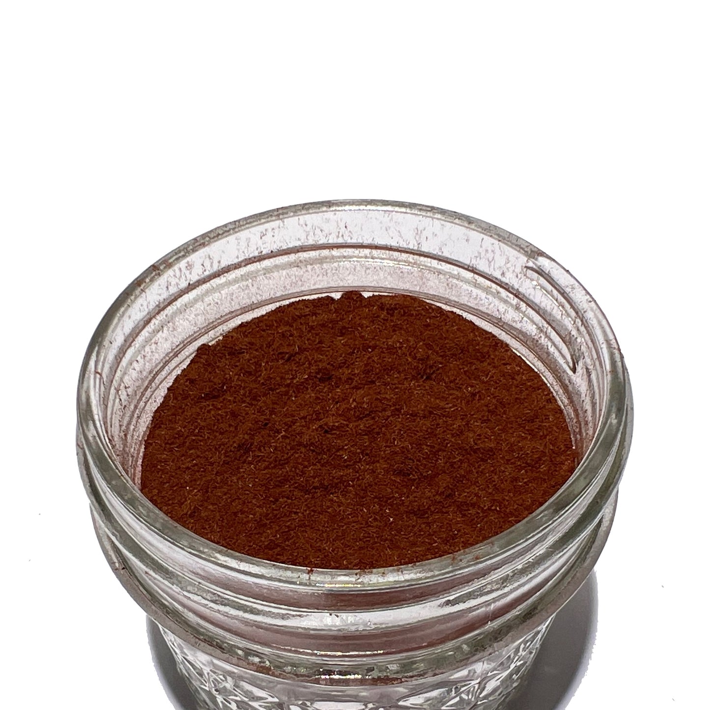 Small glass jar with flecked, reddish-brown yohimbe powder
