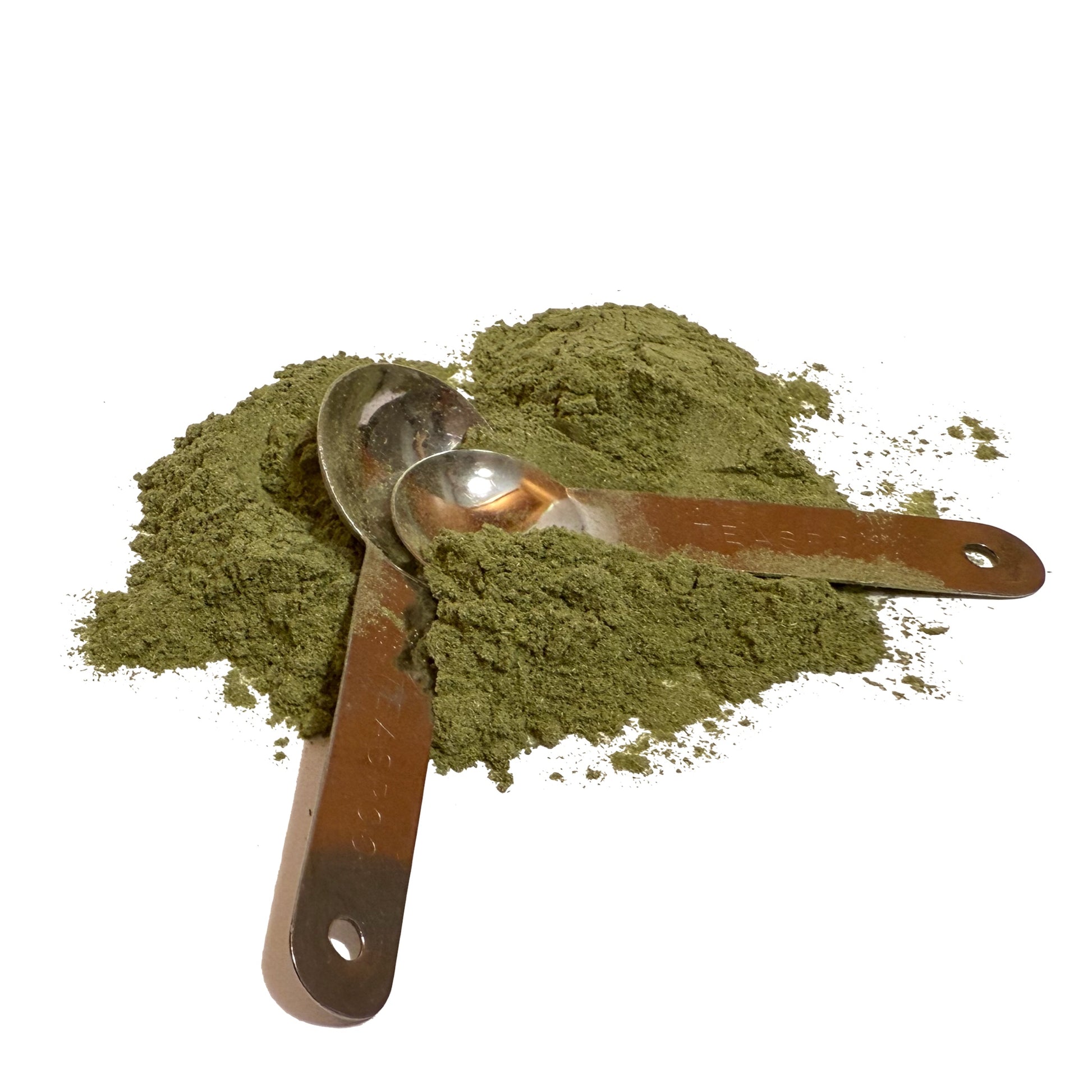 Silver measuring spoons in a pile of green barley grass powder on a white background
