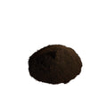 Dark brown, almost black, flecked powder piled on a white background

