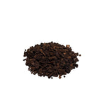 Dark brown black walnut hulls piled on a white background