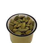 Dried cardamon pods in a vintage green, black rimmed cup