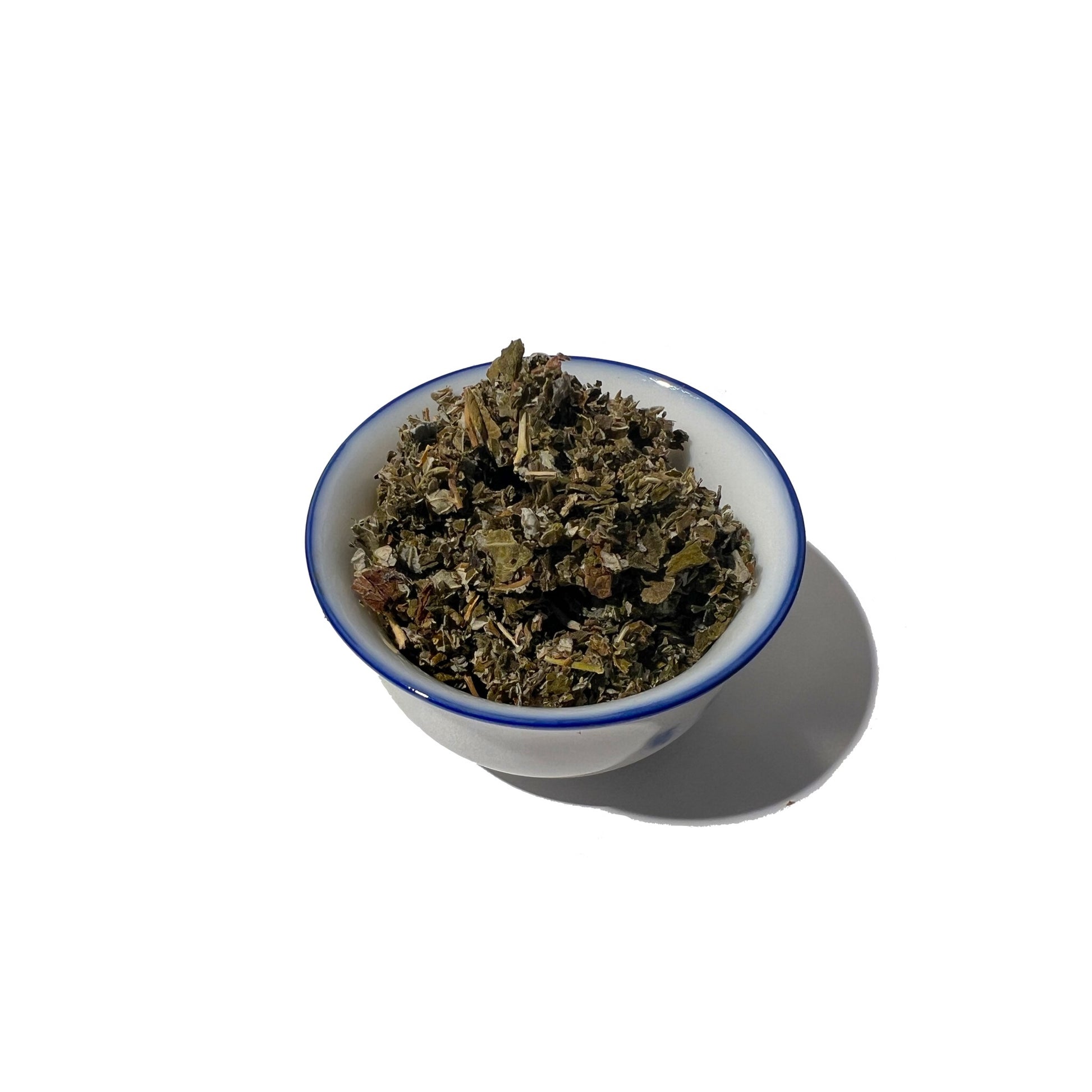 Cut and sifted raspberry leaves in a small, blue-rimmed white bowl