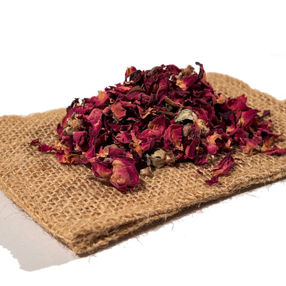 Dried red rose buds and loose petals on folded burlap