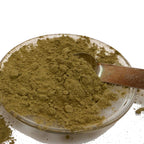 Stevia leaf powder on a clear dish with a metal half teaspoon.