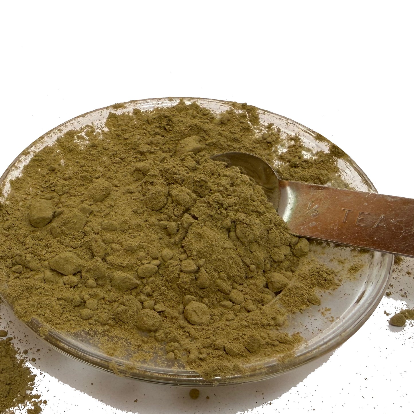Stevia leaf powder on a clear dish with a metal half teaspoon.