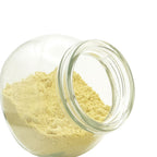 A clear glass jar tipped on its side, showing a light yellow mustard powder against a plain white background.