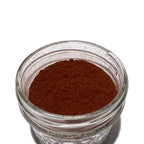 Small glass jar with flecked, reddish-brown yohimbe powder