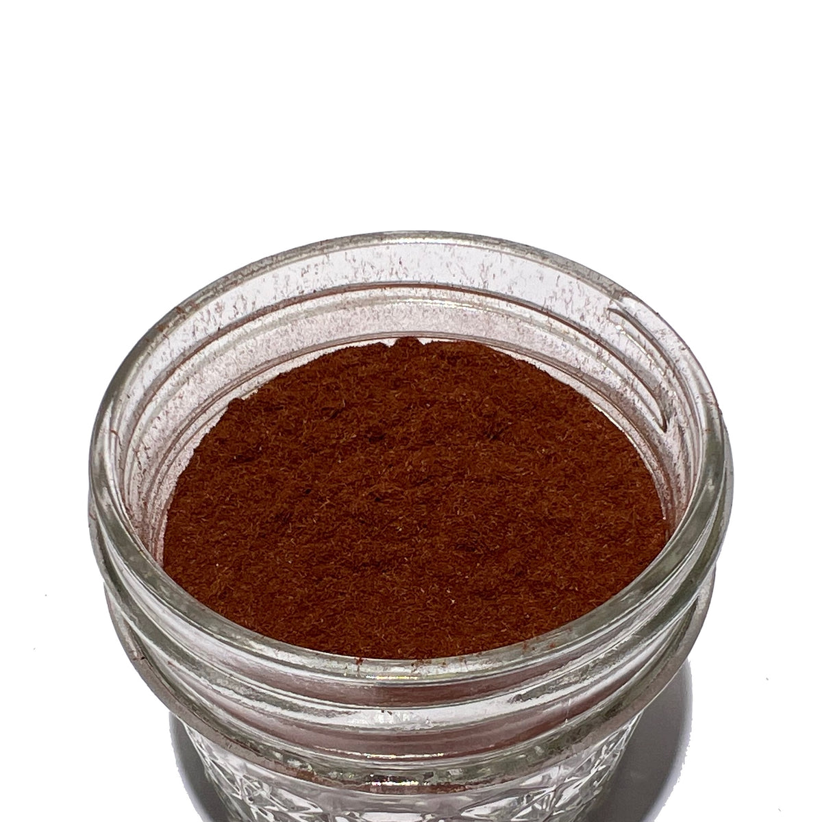 Small glass jar with flecked, reddish-brown yohimbe powder